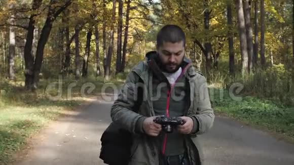 年轻的帅哥穿着夹克走在秋天的森林里关于公园性质的肖像往前走视频的预览图