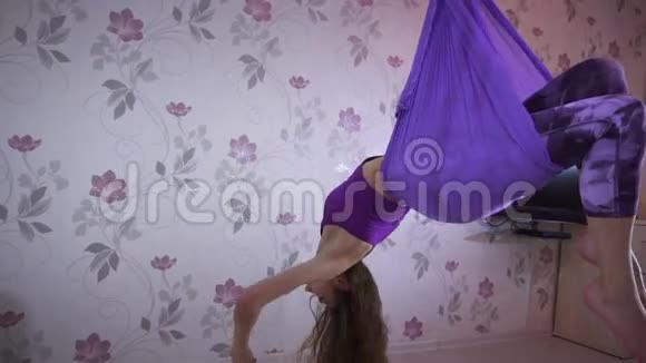 运动的年轻女子在家里用吊床做瑜伽练习视频的预览图