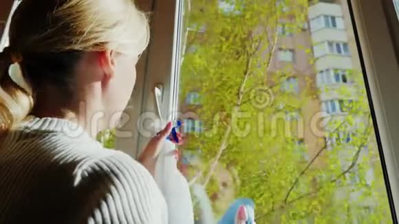 一个年轻的女人在她的公寓里洗了一扇窗户窗外一片清泉白桦树在风中摇曳视频的预览图