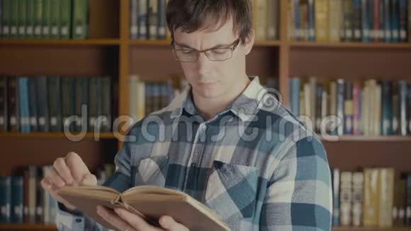 在图书馆书架附近看一本书的人的画像视频的预览图