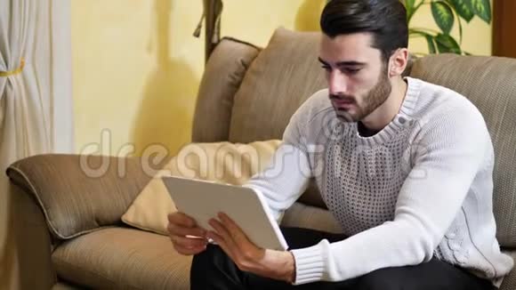 男人坐在室内视频聊天平板电脑视频的预览图