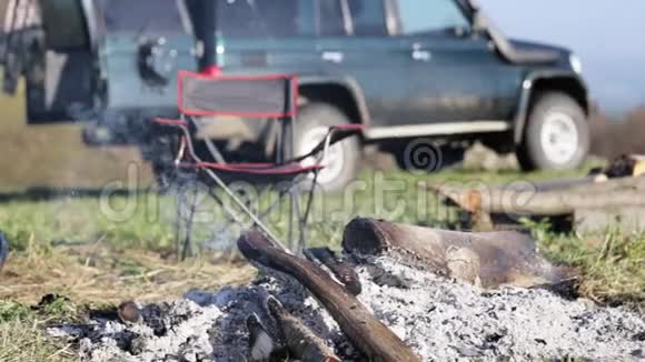 燃烧着篝火的椅子和探险队的越野车背景视频的预览图