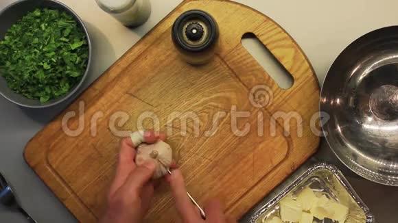 男性手在木制烹饪板上剥皮和切蒜视频的预览图