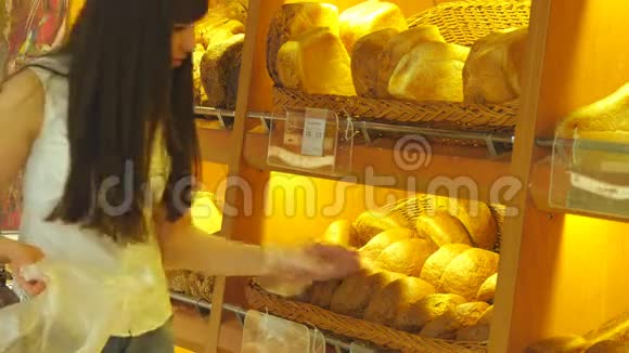 女人选择并把一个新鲜的面包放进超市的包裹里小女孩拿着一条面包视频的预览图