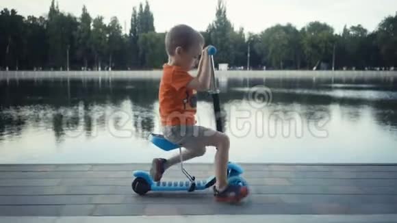 两岁快乐的小男孩在夏天的公园里骑摩托车视频的预览图