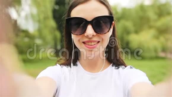 年轻女孩制作视频自拍在公园玩得开心视频的预览图