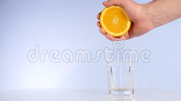 用手将橙汁慢吞吞地挤入一杯水中视频的预览图