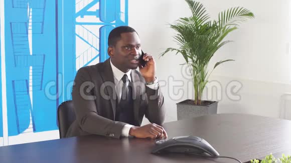 年轻的黑人商人在办公室用电话视频的预览图