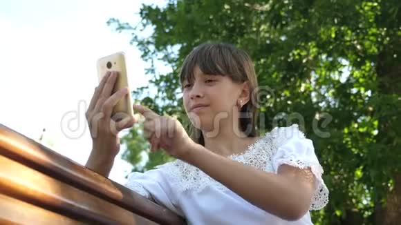 一个年轻的女孩在一个美丽的绿色公园的长凳上写一封信年轻的千禧年女性视频的预览图