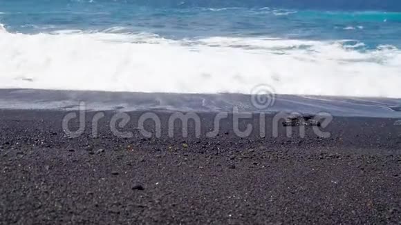 在西班牙加那利群岛的兰萨罗特的一个黑色沙滩上靠近海浪视频高清视频的预览图