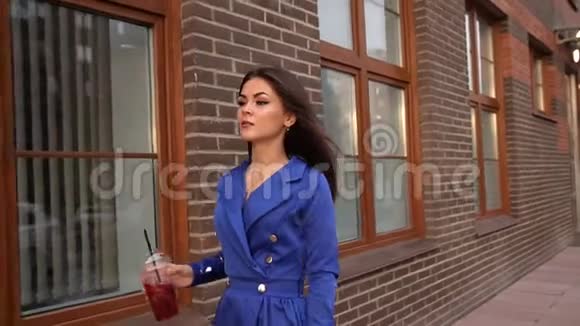 时尚年轻的黑发女人走在城市街头的肖像迷人的高加索女人穿着一件蓝色外套视频的预览图