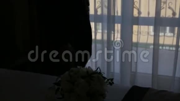 年轻快乐的新郎在黑暗的房间里拿着花束走向新娘视频的预览图
