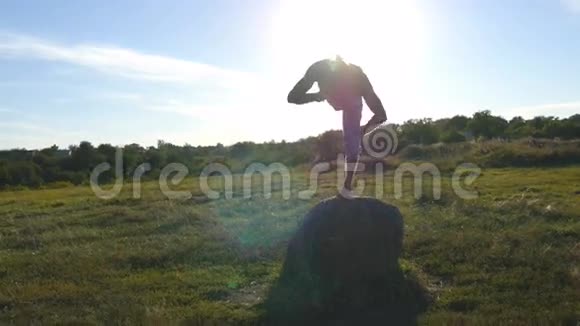 年轻的运动男子站在石头瑜伽姿势户外瑜伽在大自然中练习瑜伽动作和姿势运动员视频的预览图