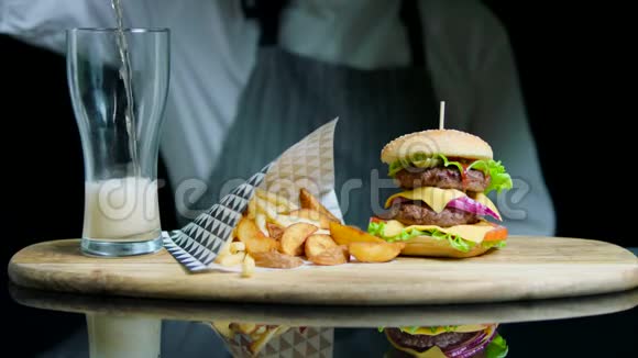 厨师提供一套美味的汉堡炸薯条将啤酒倒入木制托盘上的玻璃杯视频的预览图