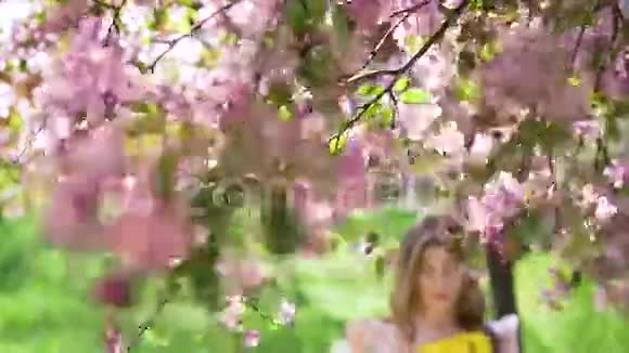 一个拿着花束的女人走在开花的树间视频的预览图