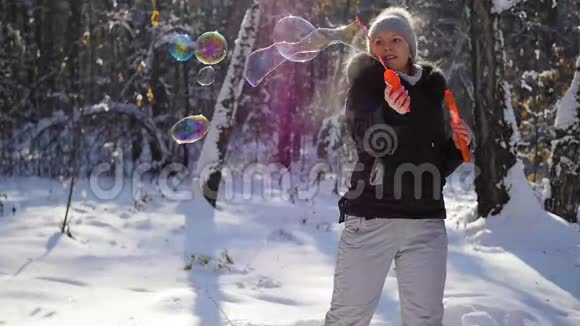 在阳光明媚的一天女孩在冬天的公园里做大肥皂泡视频的预览图