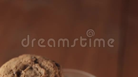 堆放在牛奶杯上的巧克力饼干木制桌子背景视频的预览图
