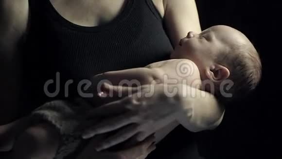 年轻的母亲用石头把孩子抱在怀里睡觉一个黑暗的房间视频的预览图