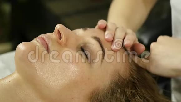 美丽的女人在水疗中心做面部按摩美容院面部皮肤护理慢动作视频的预览图