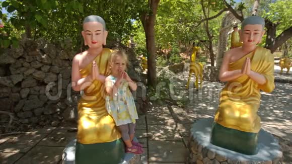 小女孩在寺庙公园坐佛雕像视频的预览图