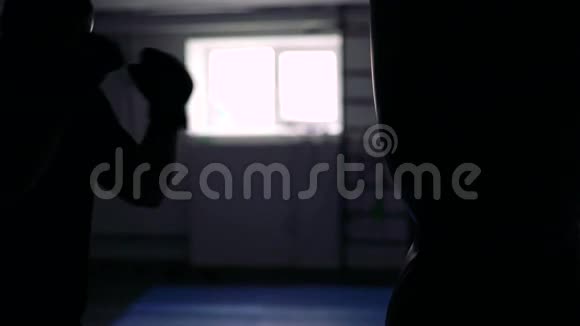 在黑暗的健身房里运动员训练带着沙袋4k视频的预览图
