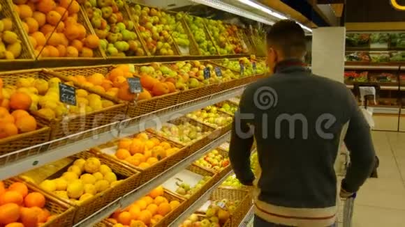 有购物车的人在超市里选择橘子视频的预览图