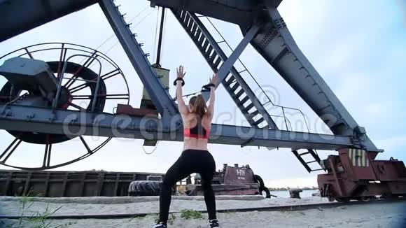 美丽的运动女性在悬吊带TRX的帮助下锻炼她的肌肉黎明时分在一台货机附近在视频的预览图
