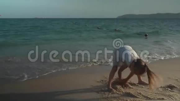 快乐的母亲和她的女儿正在南海海滩的沙滩上画慢动作股票录像视频的预览图