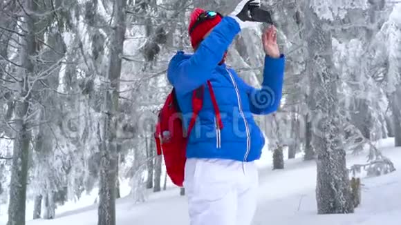 孤独的旅游女孩走在一个冬天白雪覆盖的针叶林山上在一张大自然的照片上视频的预览图