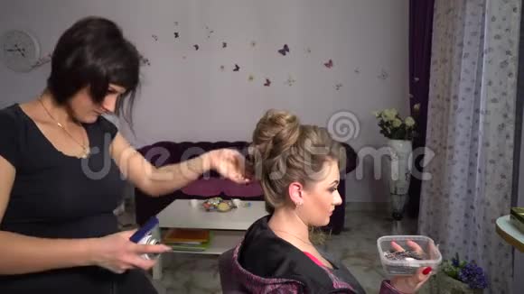 美容院理发店的年轻漂亮女孩理发师给女孩做发型美容院的金发美女视频的预览图