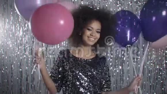 迷人的年轻女人拿着气球在银色闪光的背景上微笑视频的预览图