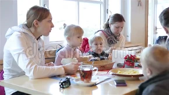孩子们和成年人在咖啡馆的桌子上吃喝视频的预览图
