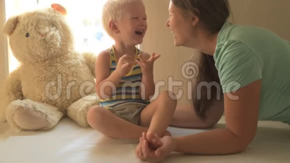 快乐的年轻妈妈正在和她美丽的小男孩玩耍婴儿爱抚亲吻拥抱奉承孩子和女人都很乐意视频的预览图
