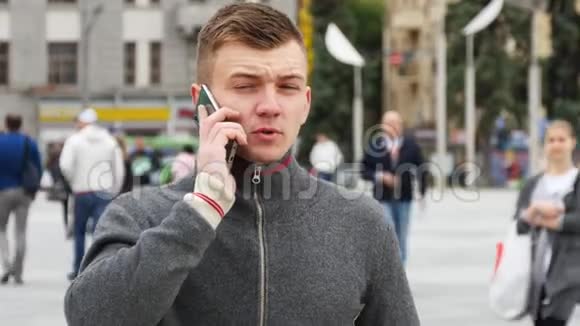 城市广场上一个年轻英俊的男人在手机上说话的肖像视频的预览图