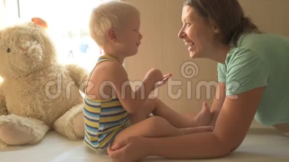 快乐的年轻妈妈正在和她美丽的小男孩玩耍婴儿爱抚亲吻拥抱奉承孩子和女人都很乐意视频的预览图