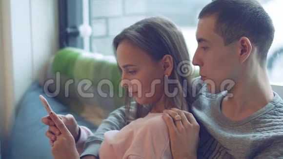 放松的爱人使用手机坐在家里客厅的沙发上视频的预览图