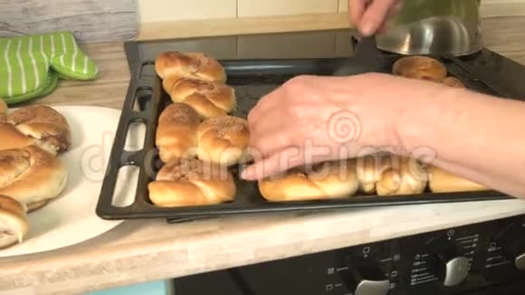 厨房里的一个女人把热糕点从一个托盘转移到一个盘子和一个铲子厨师在烤箱里煮一块糖果视频的预览图