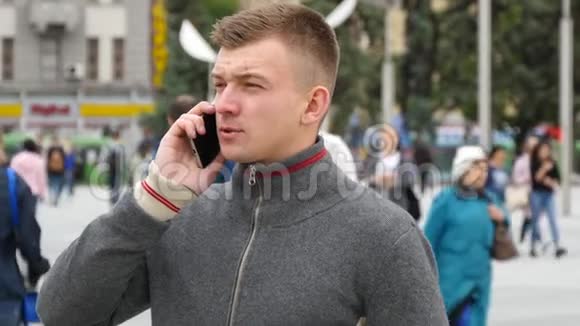 城市广场上一个年轻英俊的男人在手机上说话的肖像视频的预览图