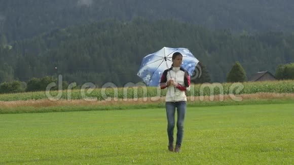 一位年轻女子撑着伞走在田野上视频的预览图