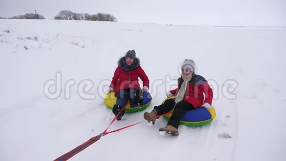 快乐的孩子们在冬天的雪地里雪橇挥舞着他们的手孩子们又笑又高兴冬天玩耍的女孩视频的预览图