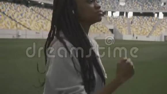 充满自信的非裔美国少女在城市体育场背景下听音乐和慢跑视频的预览图