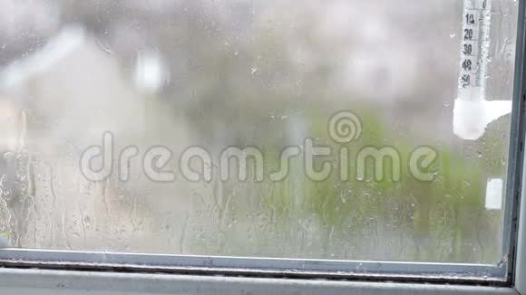 雨滴沿着窗户上的玻璃流下来显示窗外温度的温度计视频的预览图