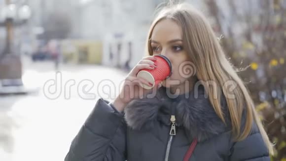 年轻漂亮的女孩在冬天在街上喝咖啡视频的预览图