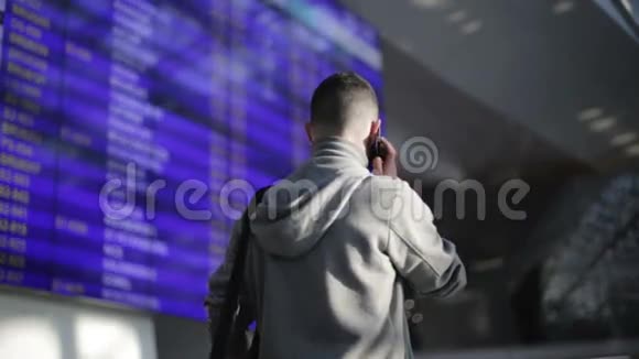 这个人正站在机场的信息板旁边用手机说话视频的预览图