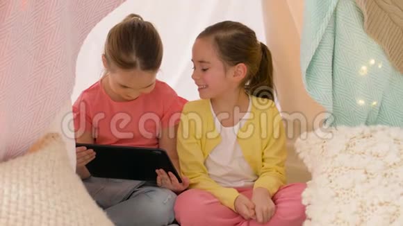 小女孩带着平板电脑在家里的儿童帐篷里视频的预览图