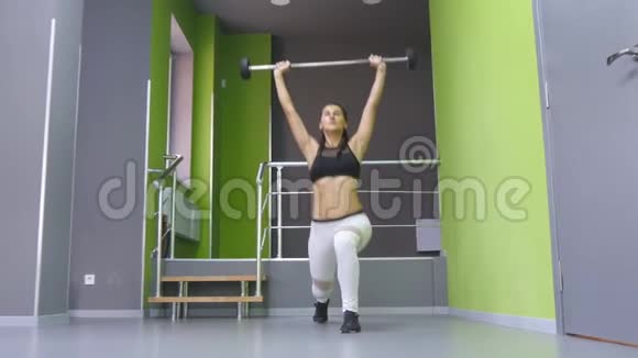 年轻的健身妇女在健身房里用杠铃和屈肌做冲刺女子训练用杠铃攻击视频的预览图