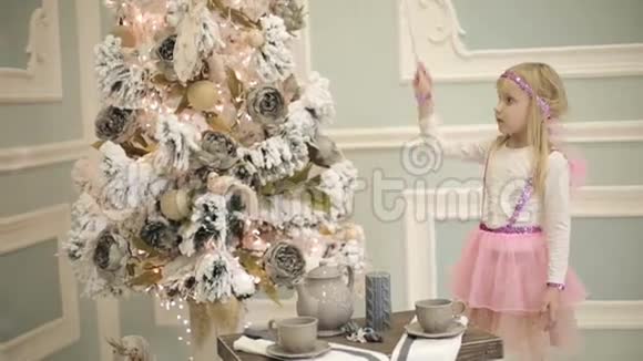穿着粉红色翅膀仙女服装的小女孩蛊惑圣诞树视频的预览图
