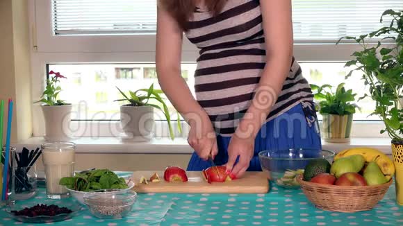 怀孕女性的胃和手在砧板上切苹果视频的预览图