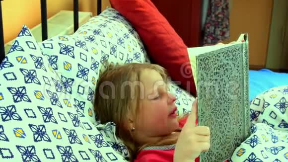 在床上的小女孩女孩看着一本老父亲的日记小女孩看着床上的一本旧书变焦相机移动视频的预览图