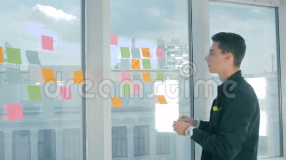 偶然的年轻商人头脑风暴写在办公室的窗户上的粘性笔记视频的预览图